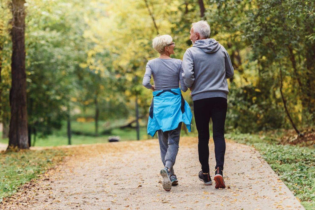 Cheerful active senior couple jogging in the park.
